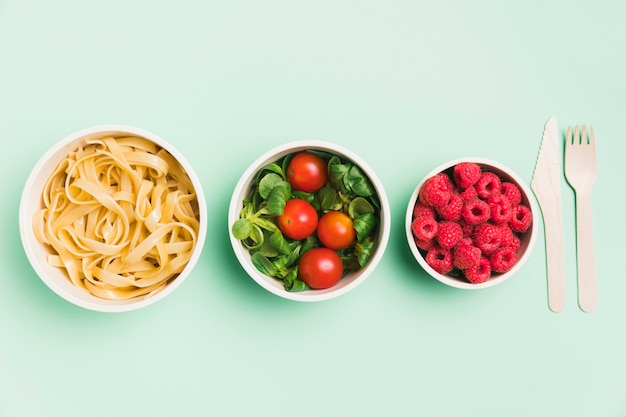 Bovenaanzicht voedsel containers met frambozen, salade en pasta