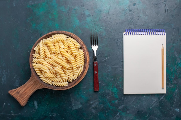 Bovenaanzicht vormde italiaanse pasta heerlijk uitziende kleine pasta op het donkerblauwe bureau