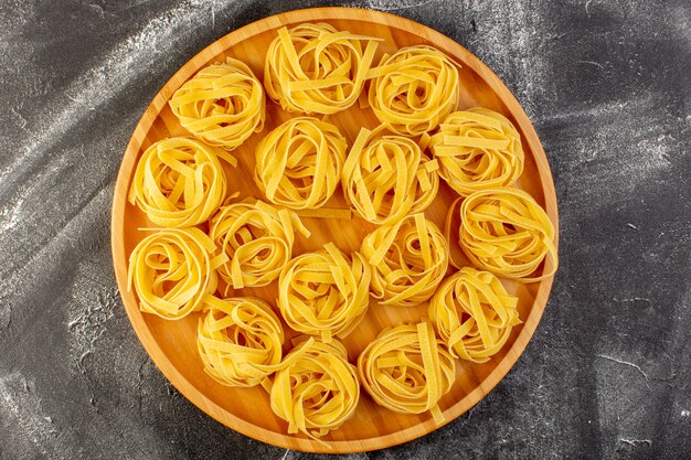 Bovenaanzicht vormde Italiaanse pasta in bloemvorm rauw en geel op de houten bureau Italiaanse rauwkost maaltijd spaghetti