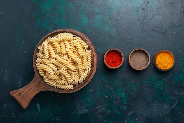 Bovenaanzicht vormde Italiaanse pasta met kruiden op het donkerblauwe bureau