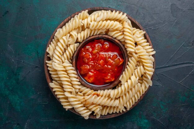 Bovenaanzicht vormde Italiaanse pasta met tomatensaus op donkerblauwe achtergrond