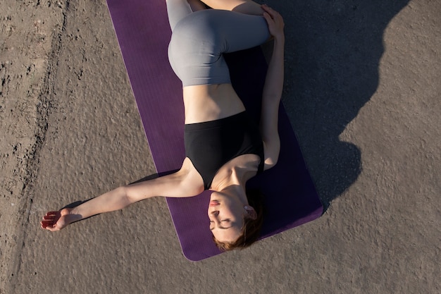 Gratis foto bovenaanzicht vrouw die zich uitstrekt op yoga mat