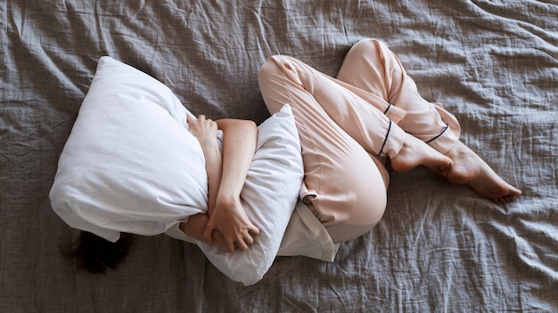 Bovenaanzicht vrouw liggend in bed met kussen