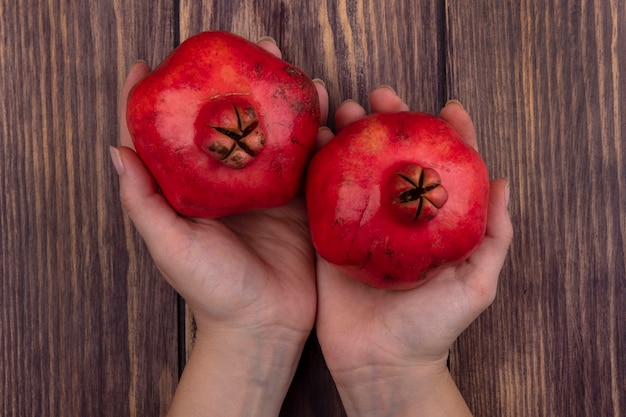 Bovenaanzicht vrouw met granaatappels in handen op houten muur