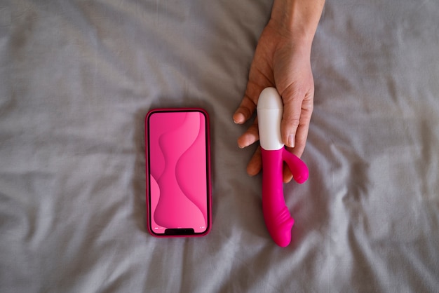 Bovenaanzicht vrouw met smartphone en vibrator