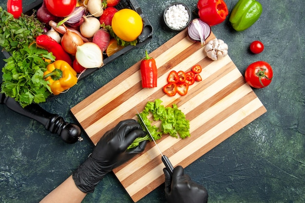 Bovenaanzicht vrouwelijke kok die verse groene salade op het grijze oppervlak snijdt