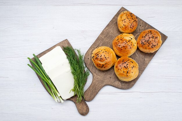 Bovenaanzicht witte kaas met vers uit de ovenbroodjes op de lichte achtergrondfoto van het voedselmaaltijdontbijt