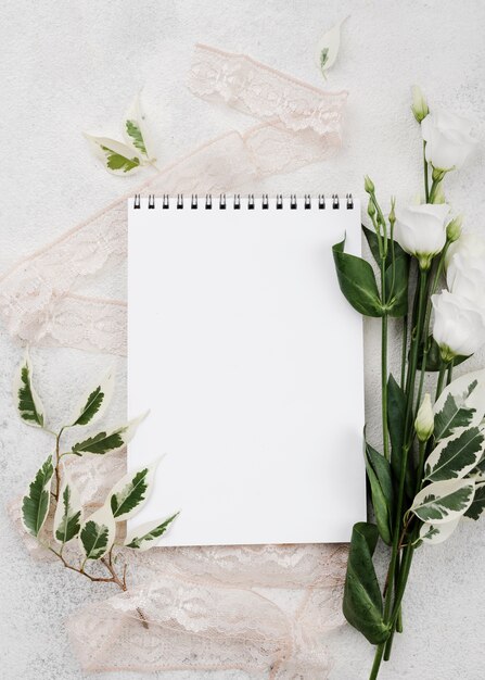 Bovenaanzicht witte Kladblok met bloemen op de tafel