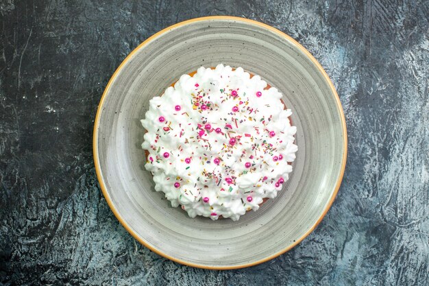 Bovenaanzicht xmas cake met banketbakkersroom op plaat op donkere achtergrond