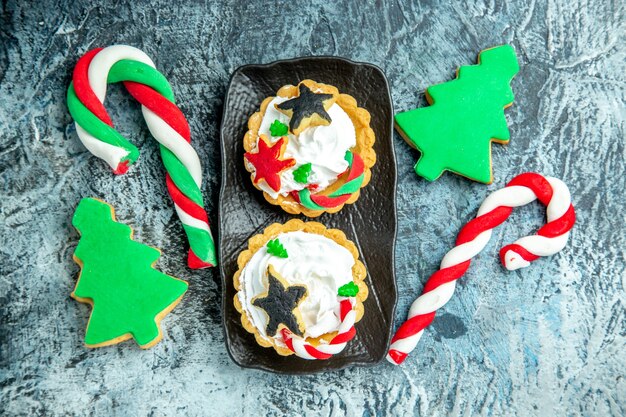 Bovenaanzicht xmas taartjes op zwarte plaat xmas snoepjes xmas tre koekjes op grijze tafel