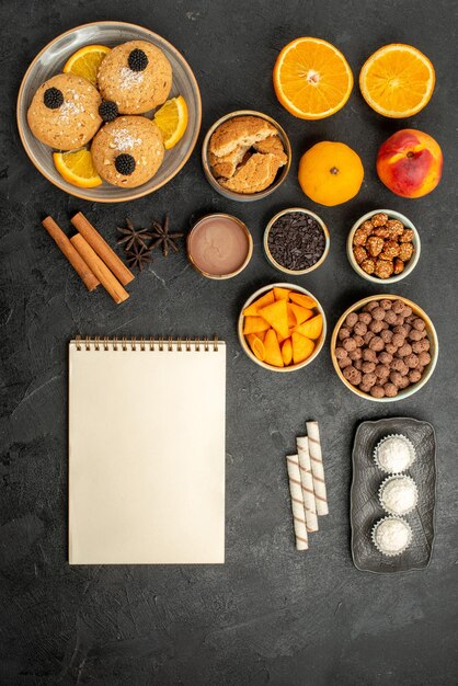 Bovenaanzicht zandkoekjes met stukjes sinaasappel en verschillende ingrediënten op een grijs oppervlak, fruitkoekje, zoete thee