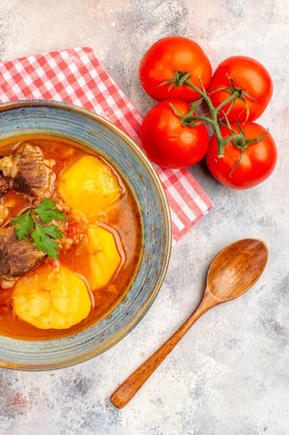 Bovenaanzicht zelfgemaakte bozbash soep keukenhanddoek houten lepel tomaten op naakt achtergrond