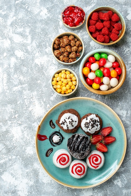 Bovenaanzicht zoete koekjes met chocoladetaart en snoepjes op lichte witte achtergrond candy sugar biscuit cake zoete thee