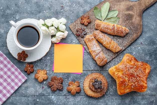 Bovenaanzicht zoete lekkere koekjes met kopje koffie en gebak zoete armbanden de grijze tafelkoekjes suiker zoete koffie