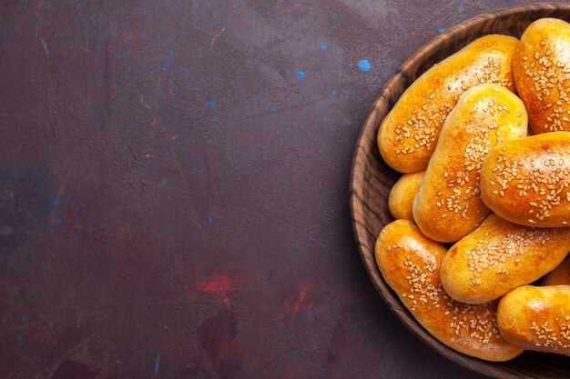 Bovenaanzicht zoete pasteitjes heerlijk gebakken deeg voor thee op donkere achtergrond maaltijd gebak deeg voedsel pasteitje