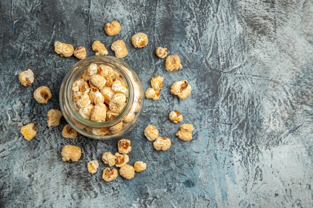 Bovenaanzicht zoete popcorn in glas kan op lichte ondergrond