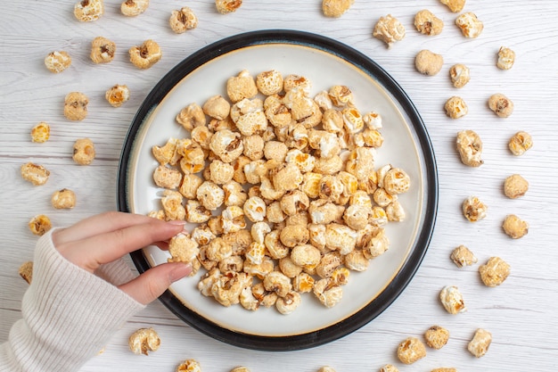 Bovenaanzicht zoete popcorn in plaat op wit oppervlak