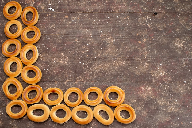 Bovenaanzicht zoete ronde crackers gedroogde en smakelijke snacks opgesteld op bruin, koekjes koekje drinken ontbijt