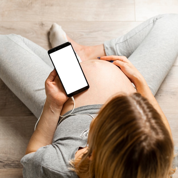 Bovenaanzicht zwangere vrouw met een telefoon