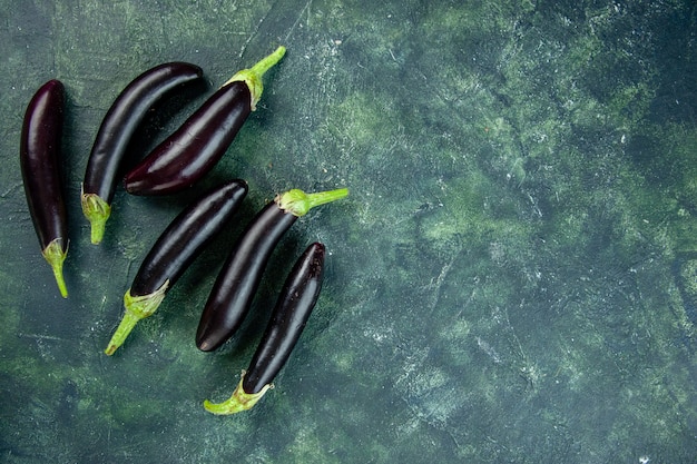 Gratis foto bovenaanzicht zwarte aubergines op donkere achtergrond rijpe salade verse groente eten diner maaltijd kleur