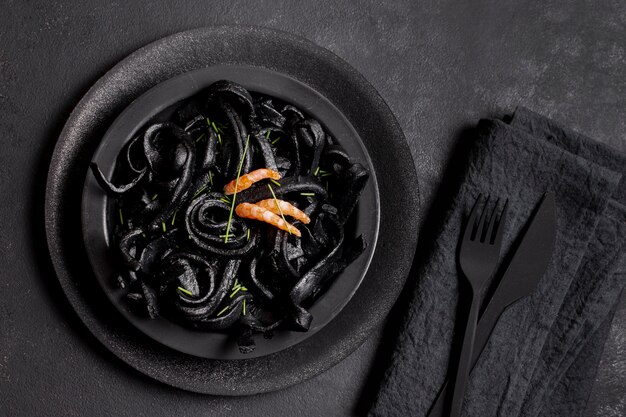 Bovenaanzicht zwarte garnalen pasta en zwart bestek