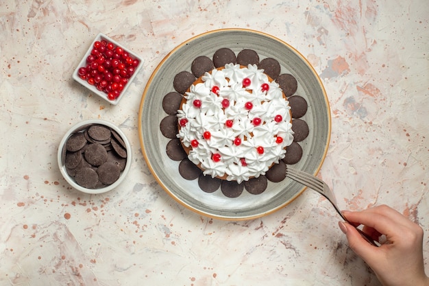 Bovenaanzichtcake met banketbakkersroombessen en chocolade in kommenvork in vrouwelijke hand