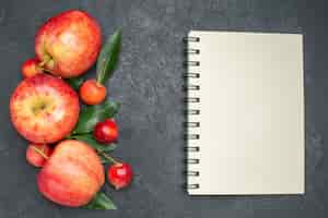 Gratis foto bovenste close-up fruit de smakelijke bessen en fruit met bladeren notebook