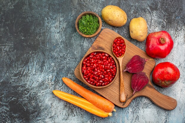 Bovenste close-up groenten het bord met granaatappel zaden wortelen bieten aardappelen kruiden