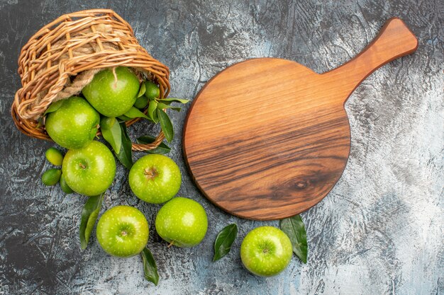 Bovenste close-up weergave appels mand met appels met bladeren naast de snijplank