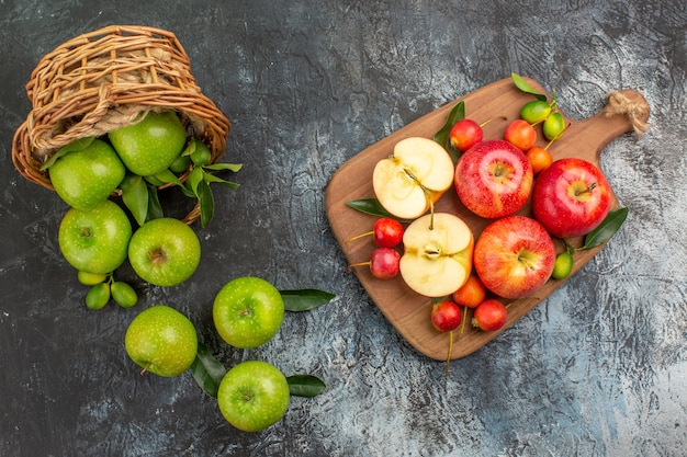 Bovenste close-up weergave appels mand met groene appels met bladeren bord met rode appels kersen