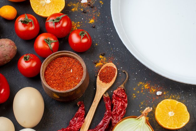 Bovenste halve weergave ronde plaat knoflook rode peper poeder in kleine kom tomaten eieren op tafel