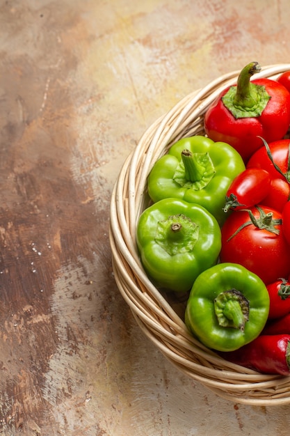 Bovenste helft weergave groene en rode pepers hete pepers tomaten in rieten mand op amberkleurige achtergrond