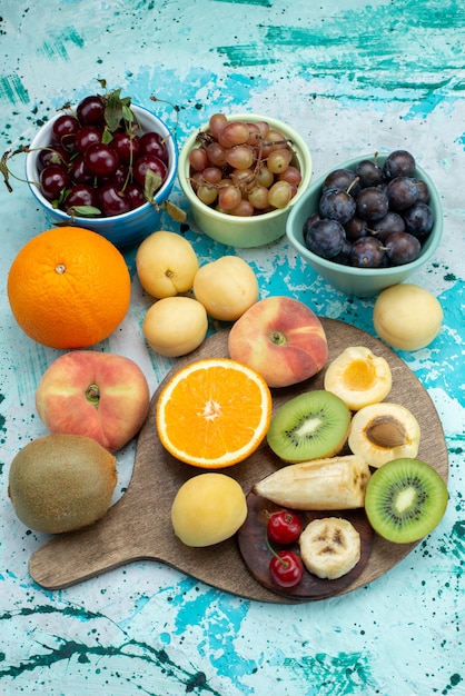 Gratis foto bovenste verre uitzicht fruitsamenstelling gesneden en geheel op het heldere bureau fruit exotische koekjessuiker