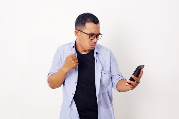 Boze aziatische man staat terwijl hij op zijn mobiele telefoon wijst. geïsoleerd op witte achtergrond