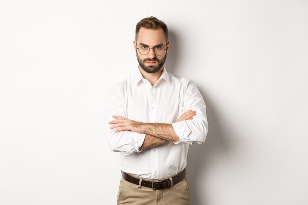Boze manager die teleurgesteld kijkt, armen gekruist op de borst en ontevreden fronsend, wit