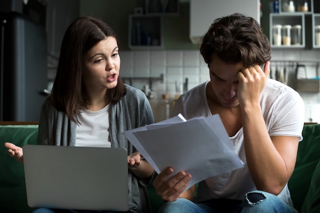 Boze vrouw die beschuldigend geschokte echtgenoot van onbetaalde rekeningen berispen