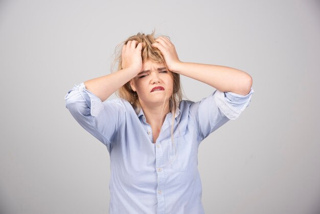 Boze vrouw die haar haar op een grijze ondergrond trekt