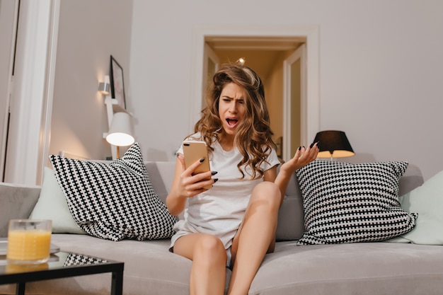 Boze vrouw in korte broek en wit t-shirt telefoonbericht lezen