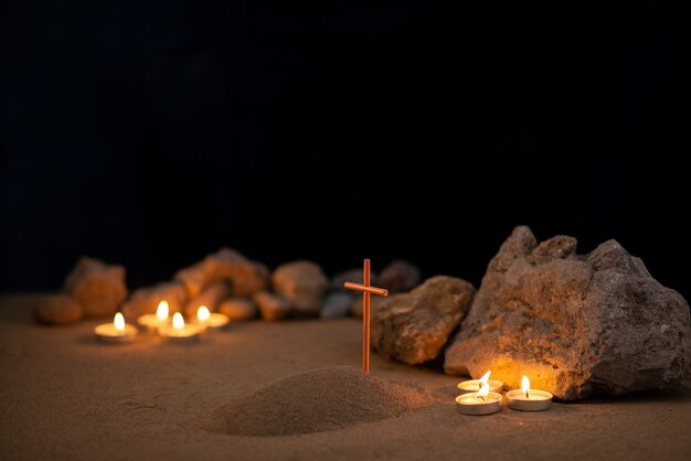 Brandende kaarsen met stenen en klein graf op zand als begrafenis ter nagedachtenis aan de dood