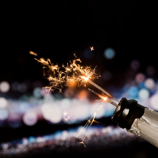 Brandsterretje in champagnefles op bokehachtergrond bij nacht