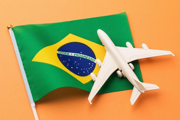 Braziliaanse vlag en speelgoedvliegtuig op een gekleurde achtergrond, concept van vlucht naar brazilië, bovenaanzicht