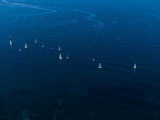 Brede luchtfoto van kleine witte zeilboten drijvend in de oceaan dicht bij elkaar