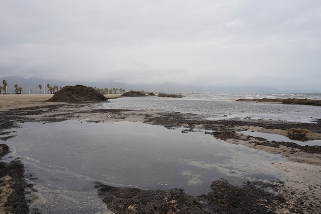Gratis foto breed shot van een kust met een stapel zwart zand