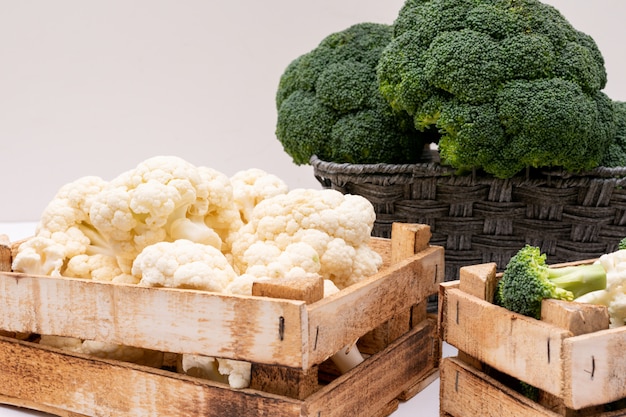 Gratis foto broccoli en bloemkool in houten kist en broccoli in mand