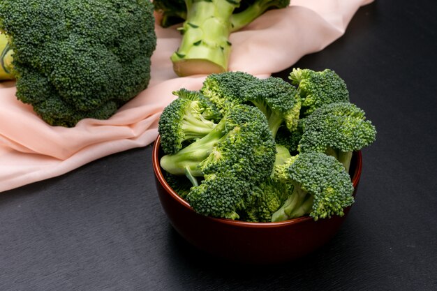 Broccoli in keramische kom en op roze doek