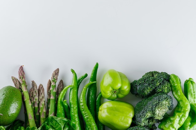 Gratis foto broccoli met asperges, paprika, avocado en sla op een witte tafel