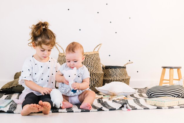 Broer / zus spelen met speelgoed op gestreepte doek