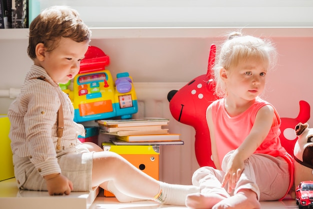 Broers en zussen zitten met speelgoed poseren