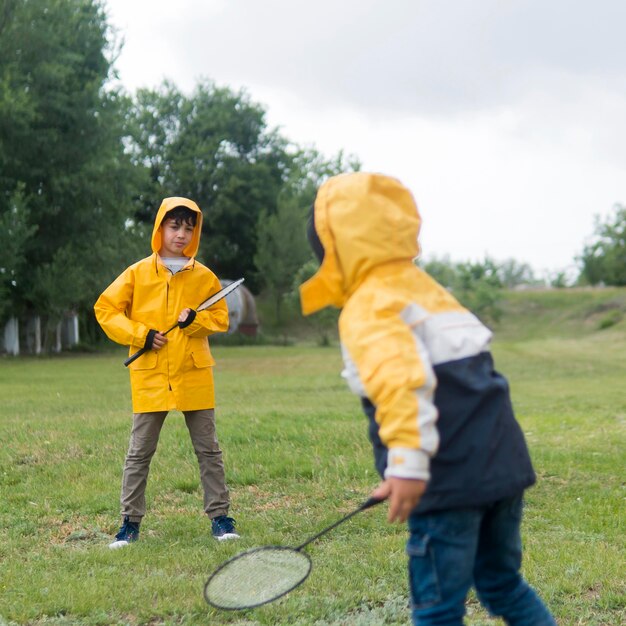 Broers in regenjas badminton spelen