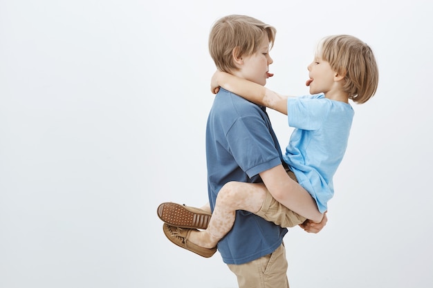 Broers vinden altijd een manier om samen plezier te hebben. zorgeloos schattig mannelijke broers en zussen tong aan elkaar tonen, knuffelen